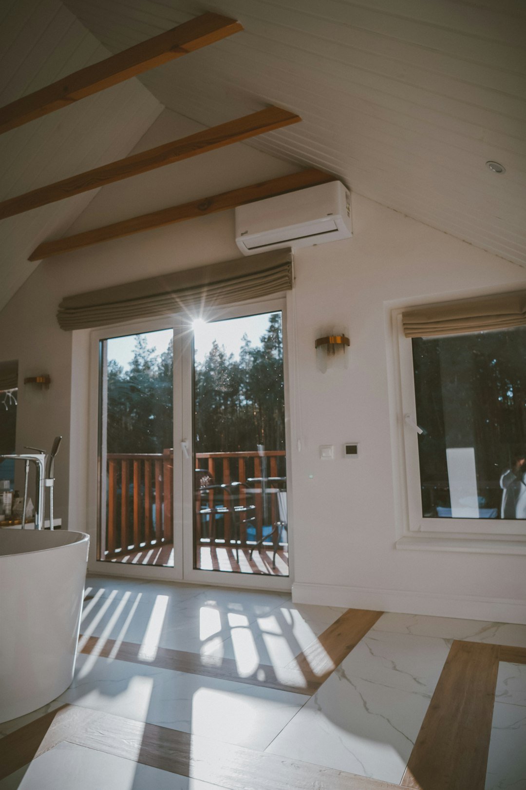 a room with a wood floor and a glass door with a view of trees and a patio with