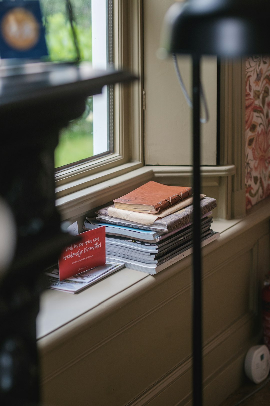 A stack of books sitting on top of a window sill