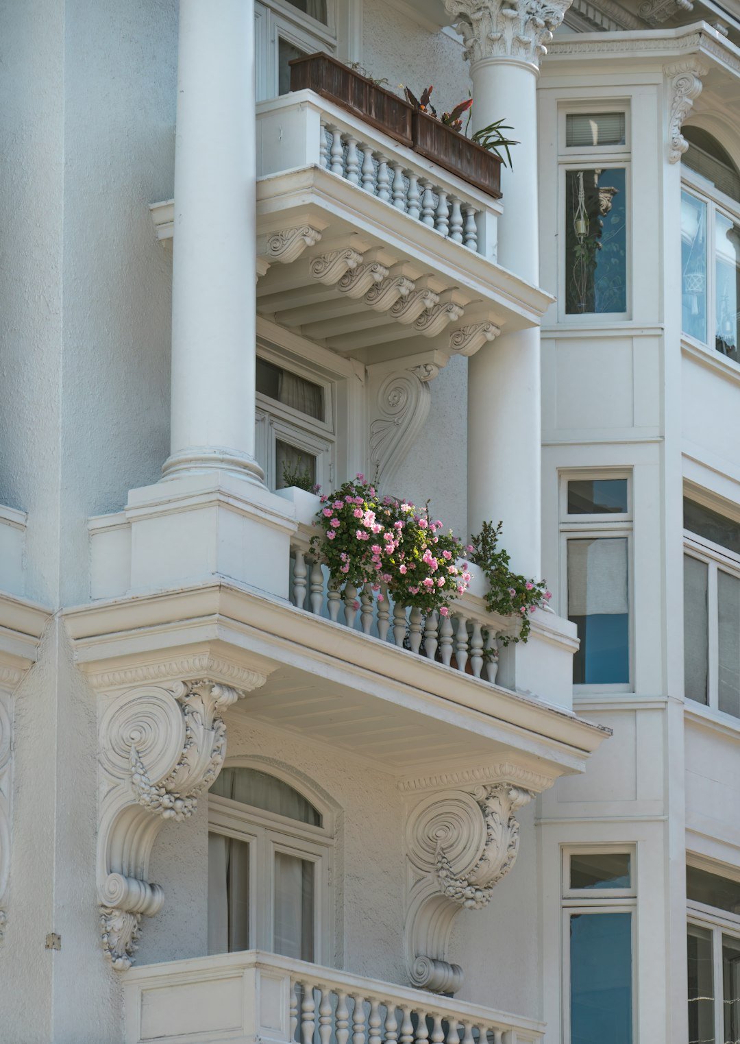 a white building with balconies and flowers on the balconies