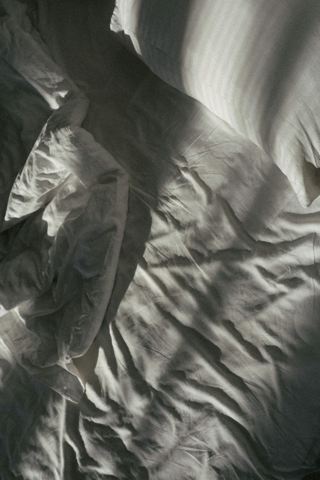 an unmade bed with white sheets and pillows