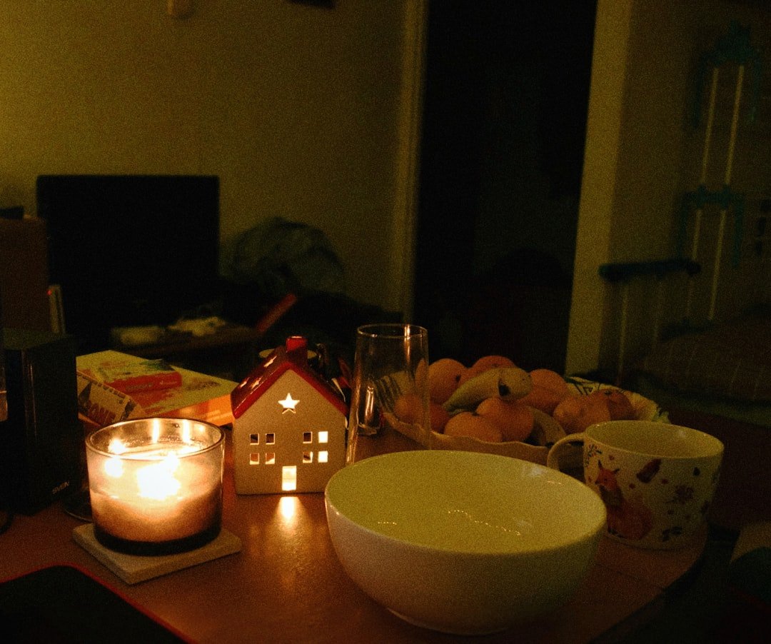 a table topped with a bowl of fruit and a lit candle