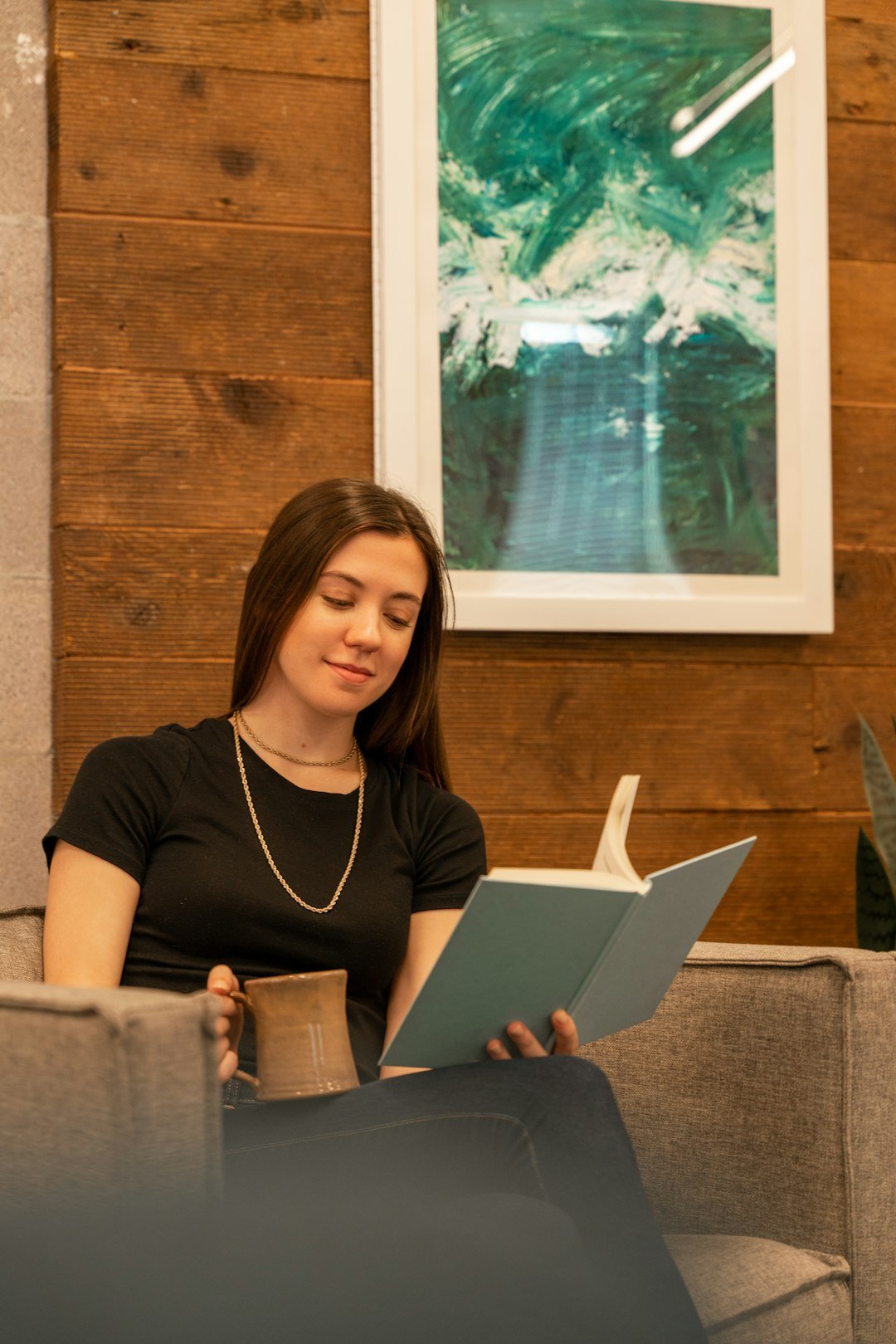 a woman sitting on a couch reading a book