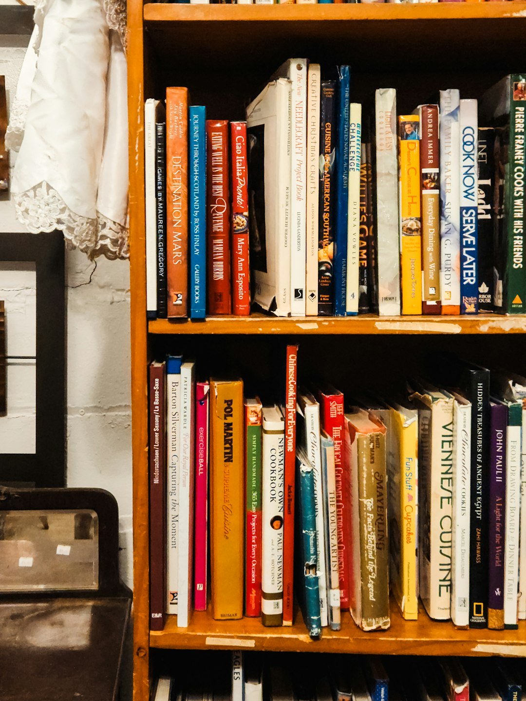 A bookshelf filled with lots of books next to a suitcase