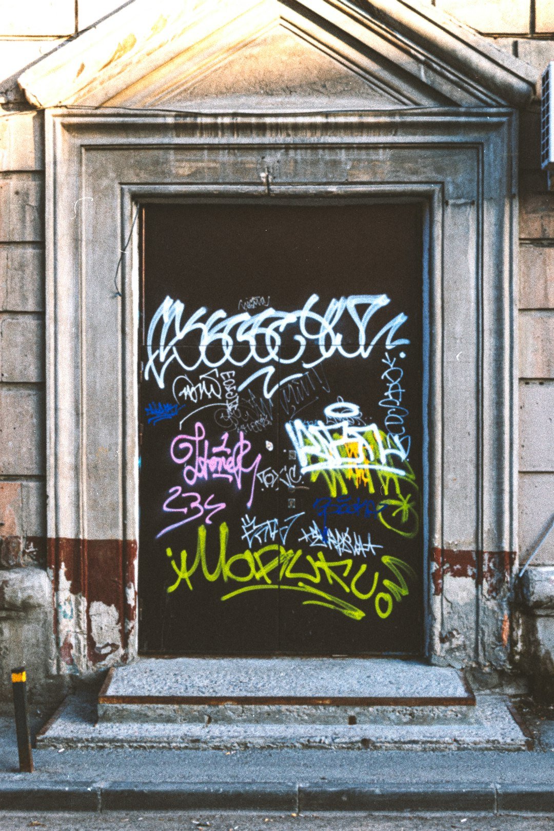 a door covered in graffiti in front of a building