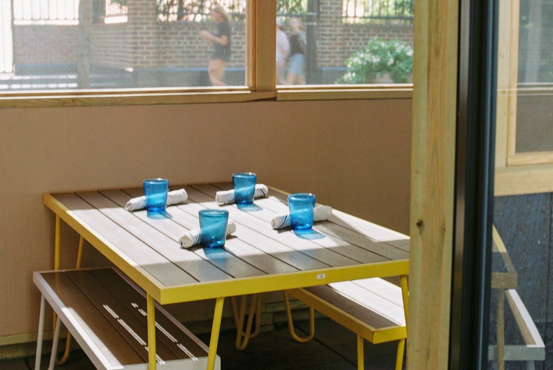 A table with four chairs and a bench in front of a window