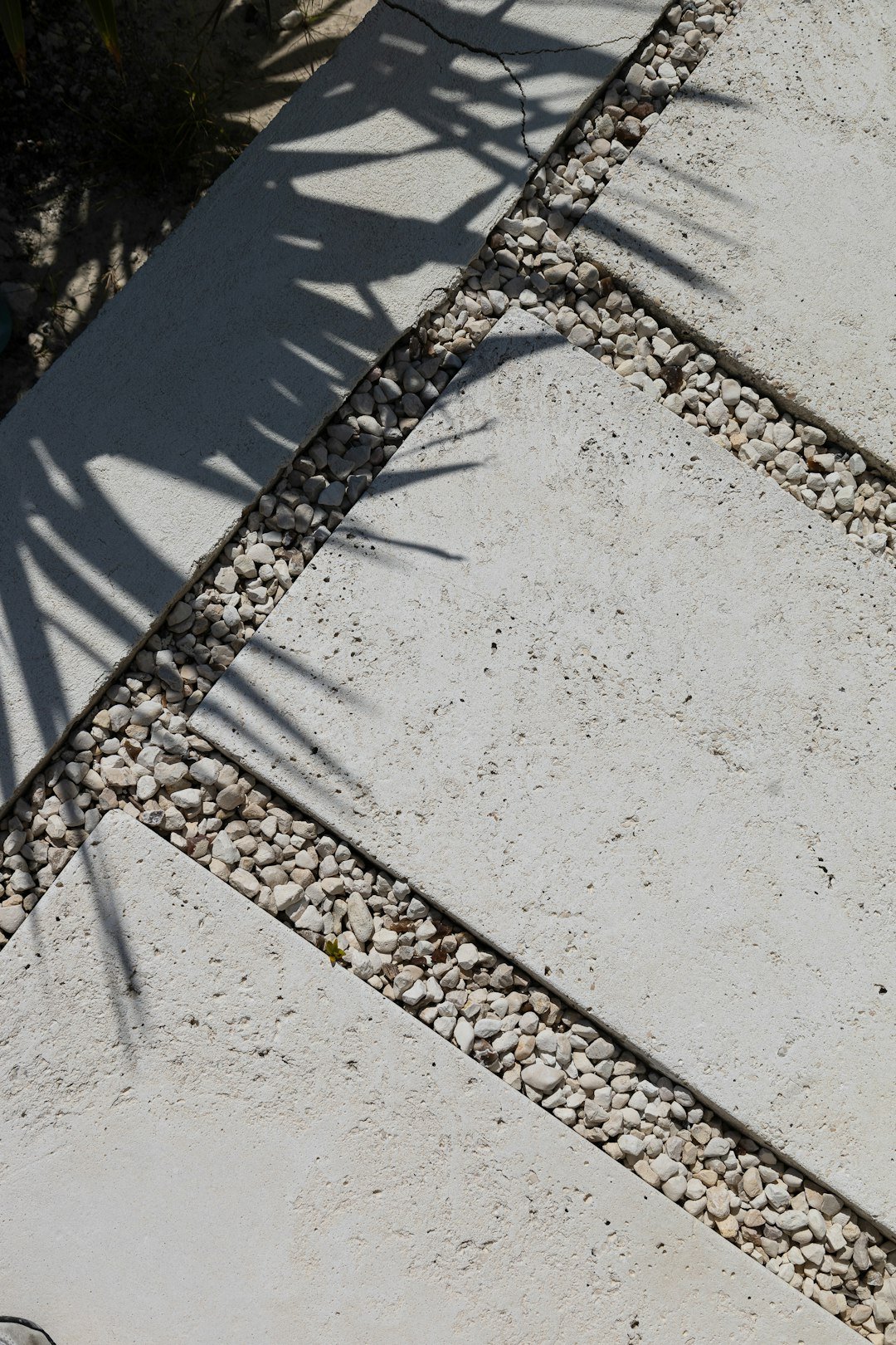 Stone pathway with decorative gravel and leaf shadows.