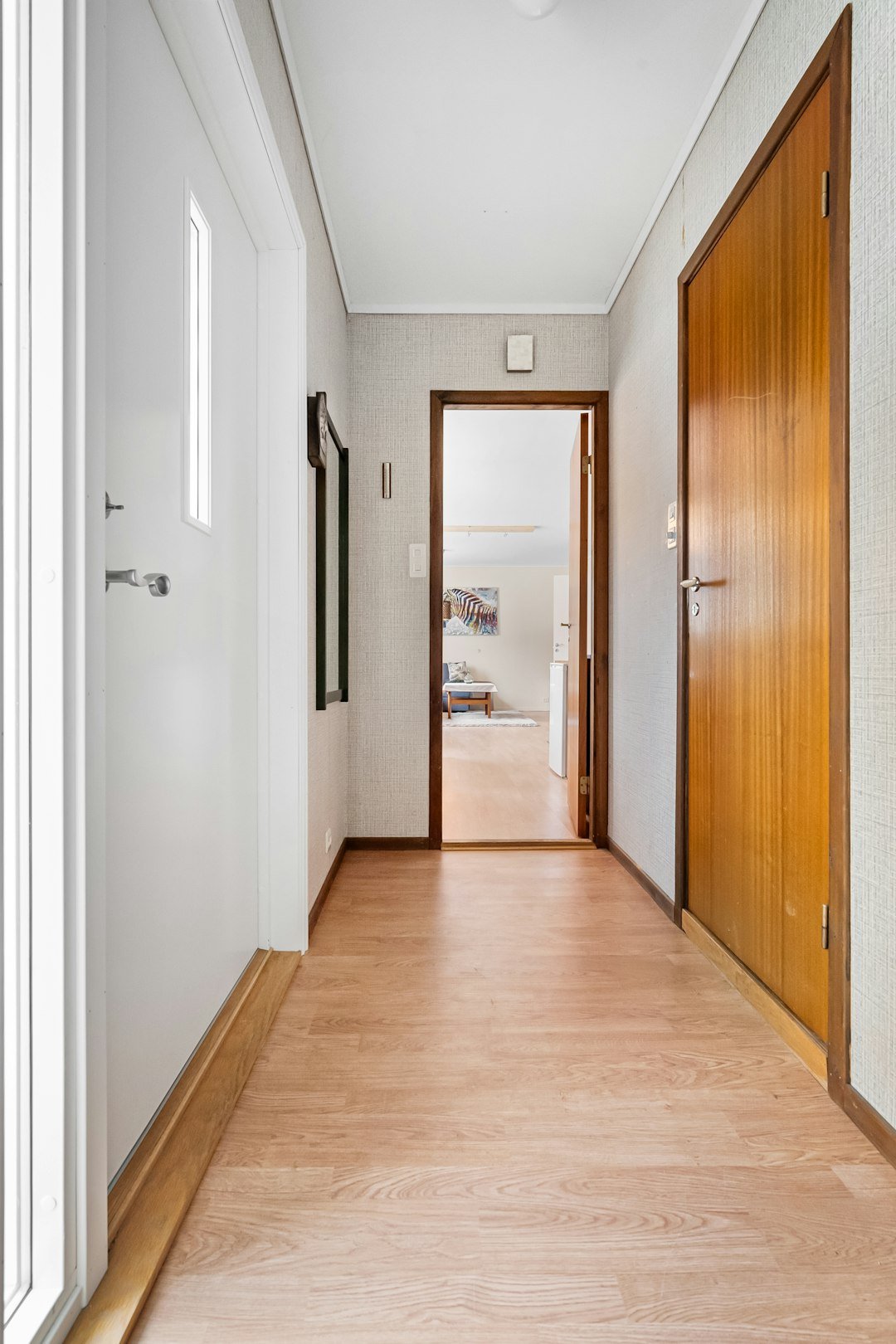 A long hallway with wooden doors and white walls