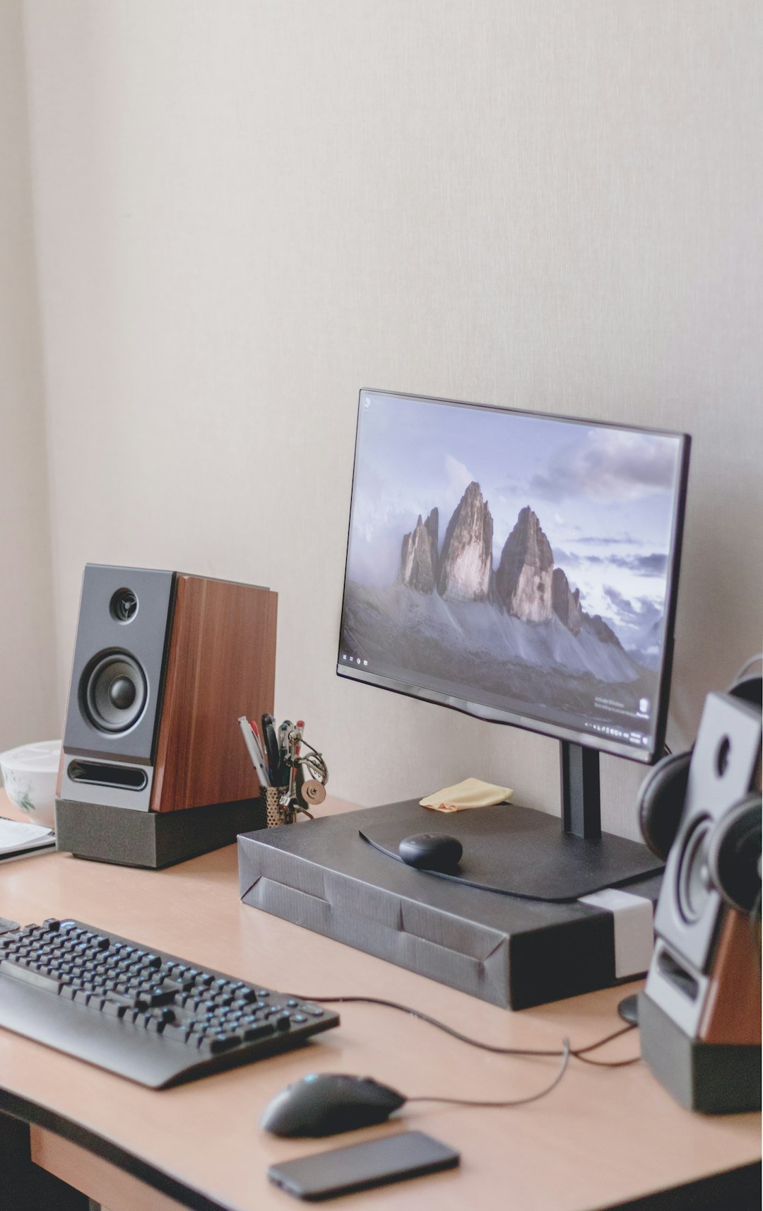a computer desk with a keyboard, mouse, speakers and a monitor