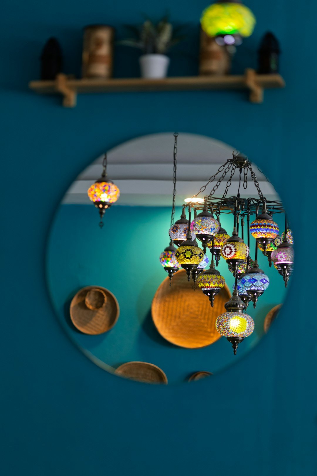 Decorative lamps and shelf reflected in a round mirror.