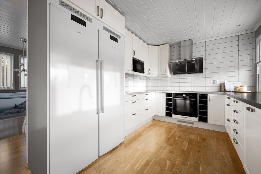 A kitchen with white cabinets and a wooden floor