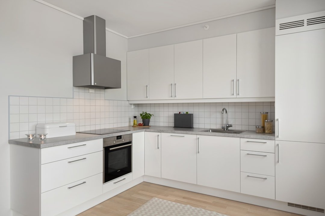 A kitchen with white cabinets and a white rug