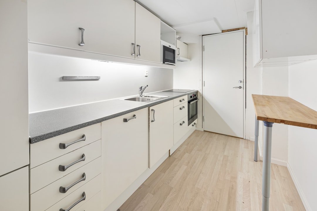 A kitchen with white cabinets and a wooden table