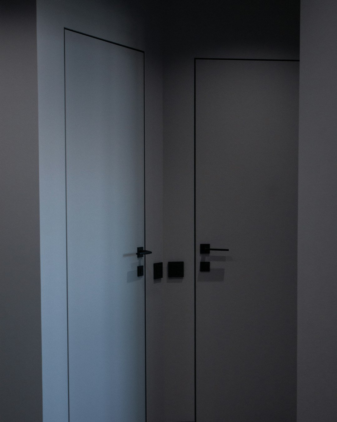two white doors in a room with a black floor