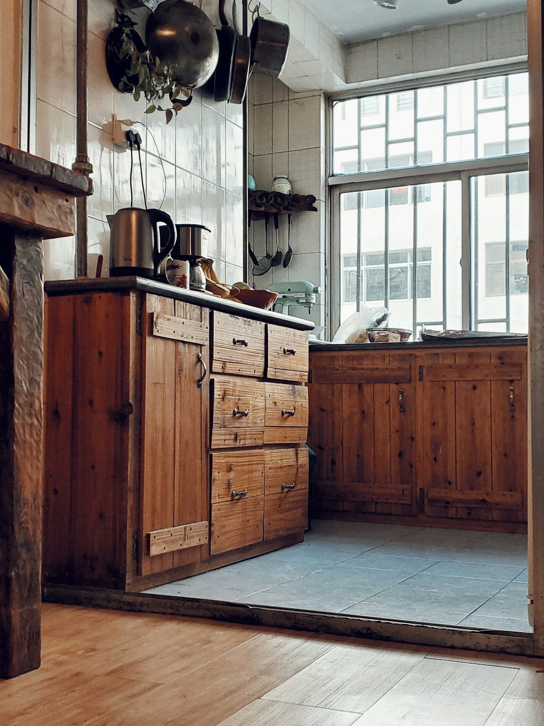 a kitchen with wooden cabinets and pots hanging from the ceiling