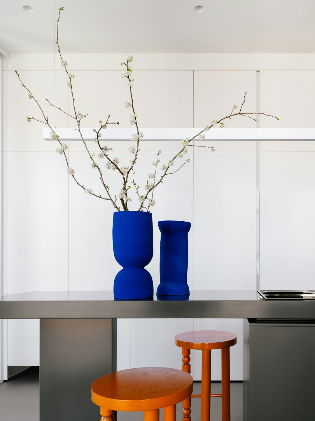 Bright blue vases with floral branches on the countertop.
