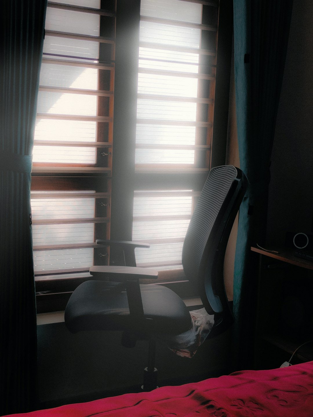 a chair sitting in front of a window next to a bed