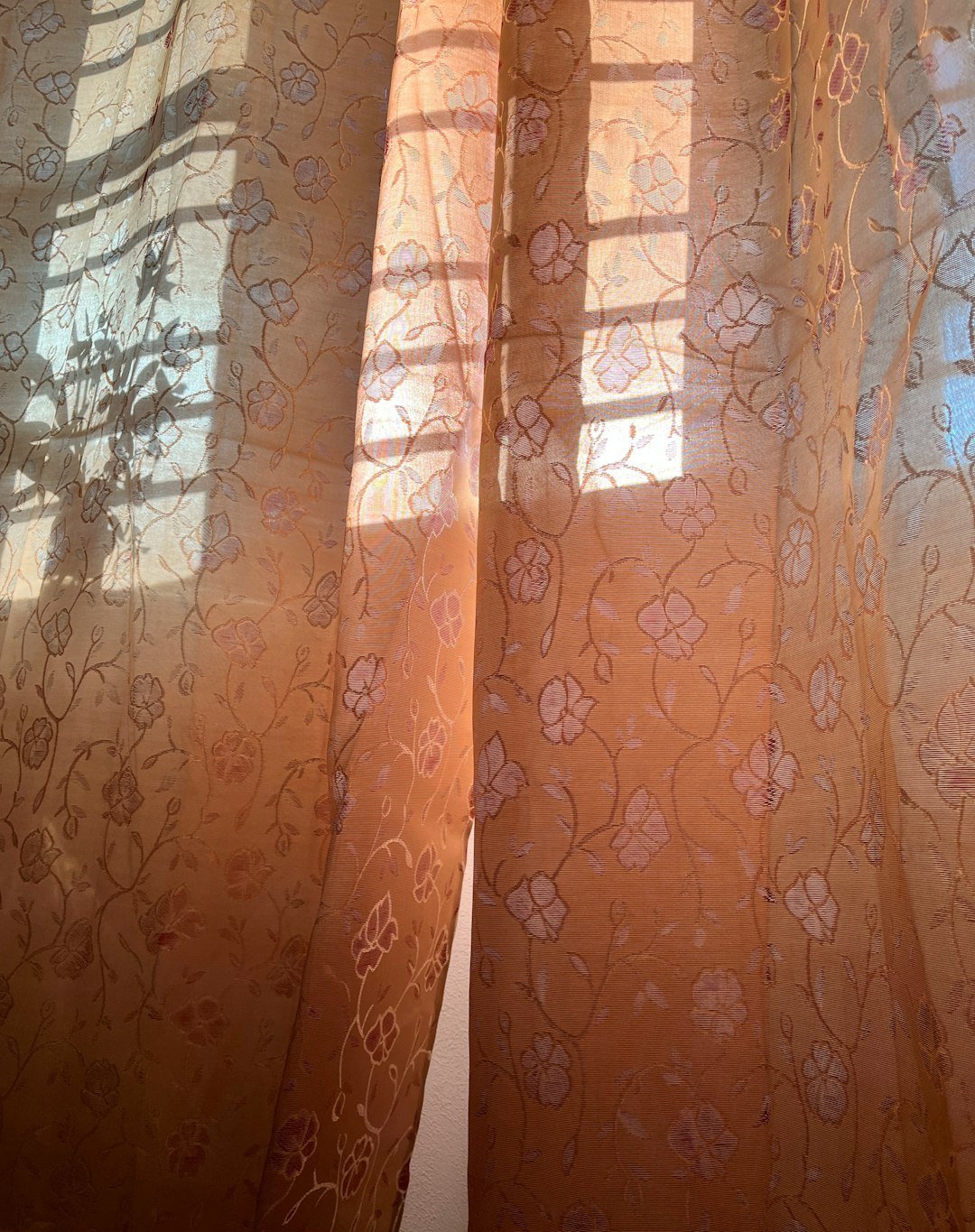 a window with sheer curtains and a cat sitting on the window sill