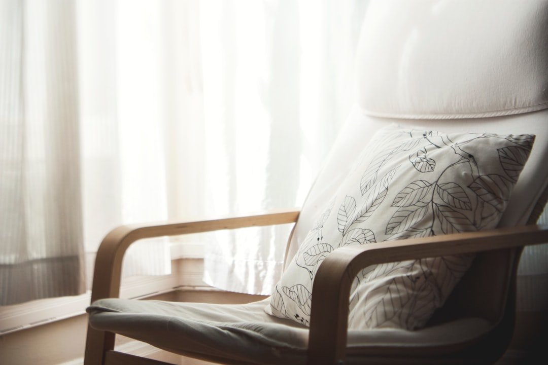 white and grey leaf-printed pillow on armchair